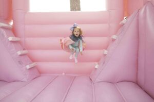 Little girl turning 5 in a pink jump house 