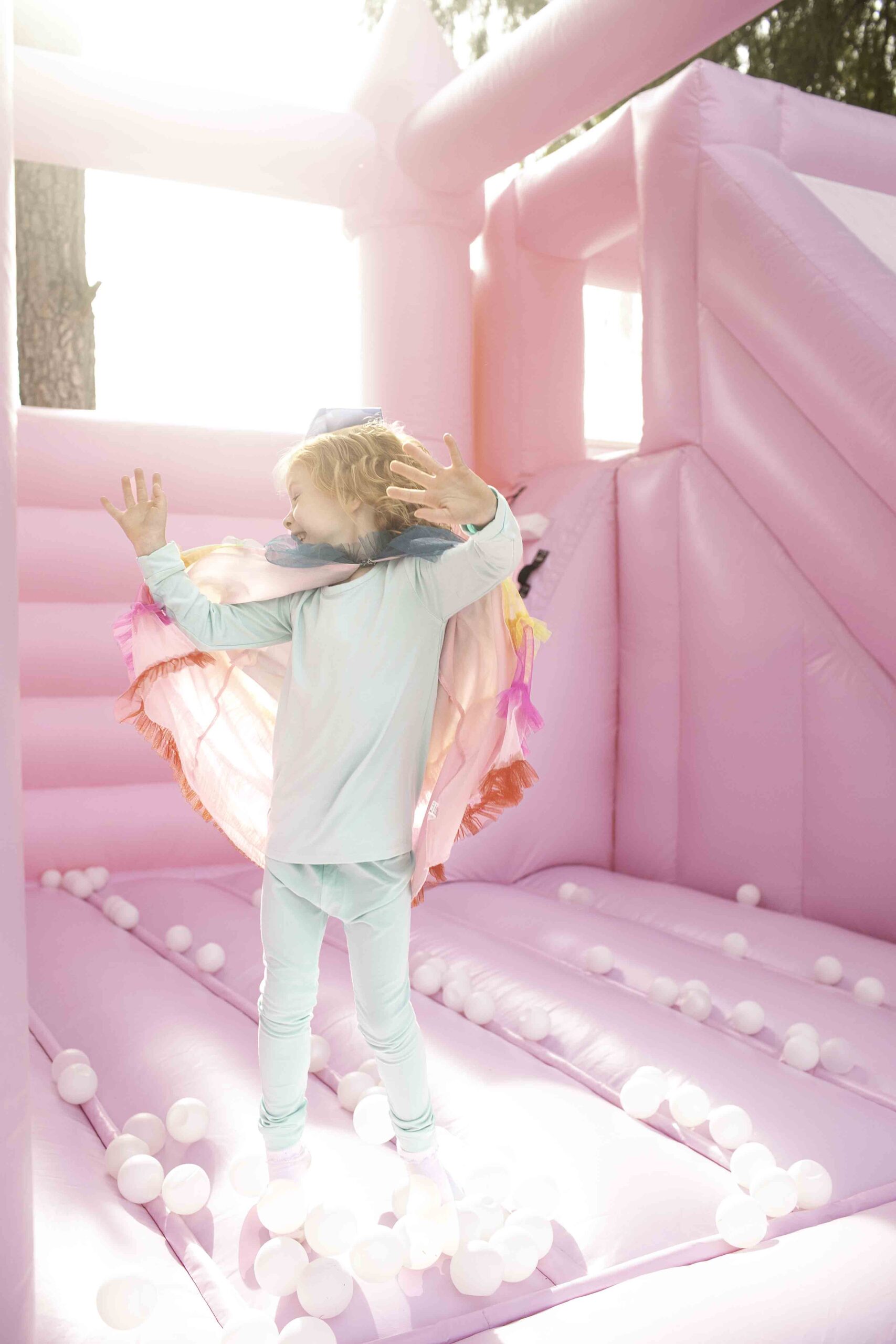 Little girl turning 5 in a pink jump house