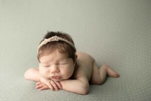 Newborn Baby Girl with head on hands 