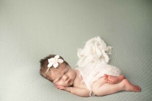 Newborn Baby Girl snuggled up with a white wrap 