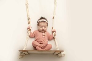 Newborn Baby Girl on a swing in a pink outfit 