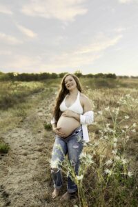 Maternity session with mama in white shirt in nature in flowers