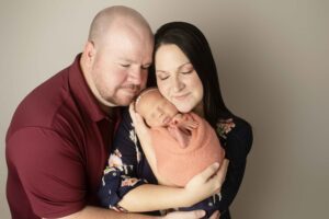 Newborn Baby Girl in pink wrap with Mom and Dad