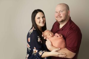 Newborn Baby Girl in pink wrap with Dad and mom