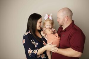 Newborn Baby Girl in pink wrap with Dad, mom and big sister