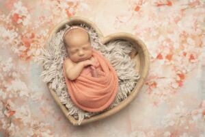Newborn Baby Girl in Pink wrap in heart prop