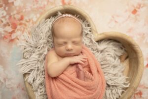 Newborn Baby Girl in Pink wrap in heart prop
