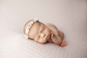 Newborn Baby Girl on Purple Blanket with hands on face