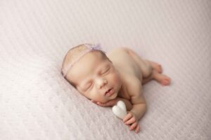 Newborn Baby Girl on Purple Blanket holding a heart