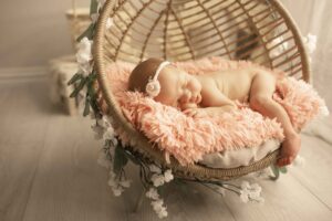 Newborn Baby Girl in boho basket near window with flowers