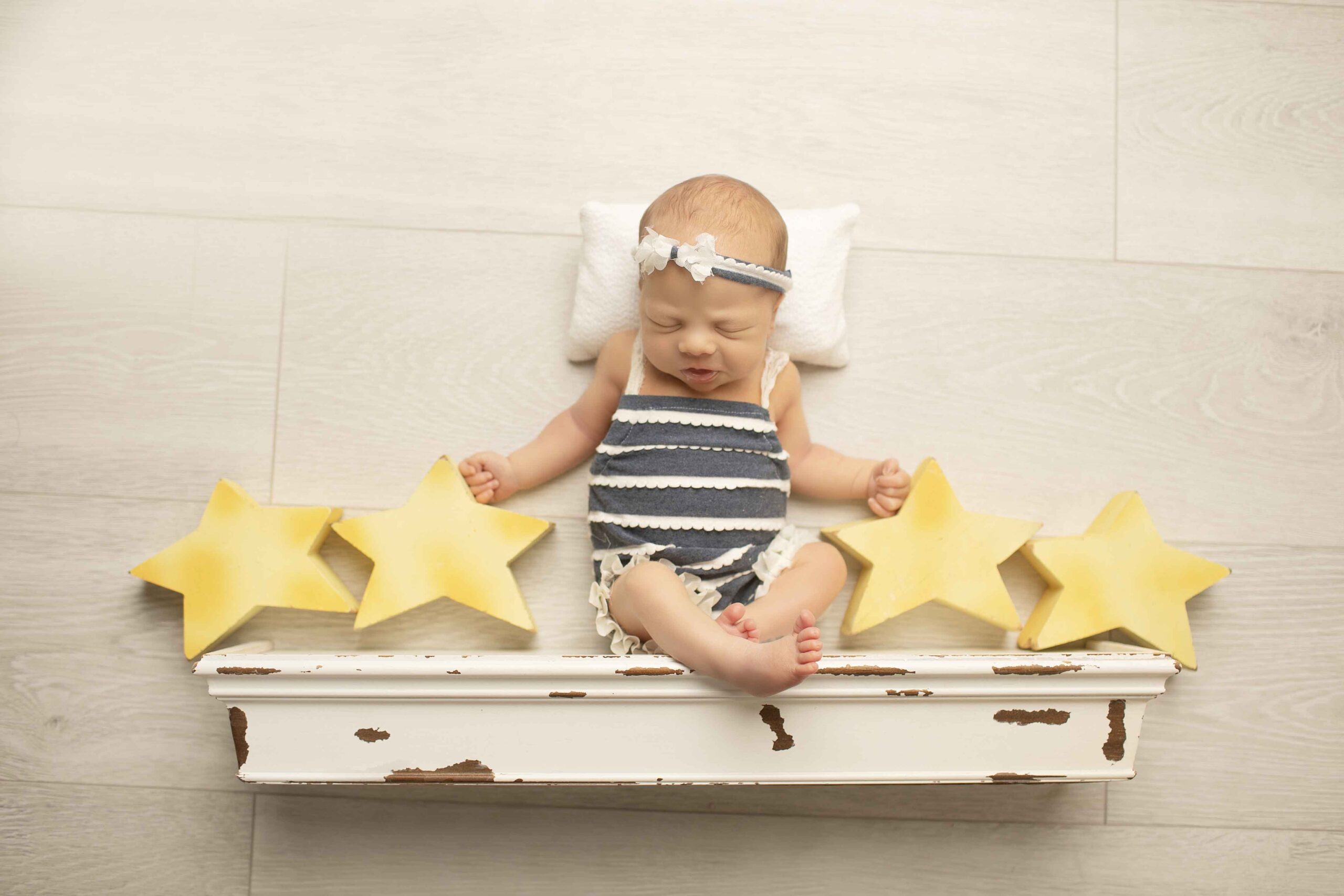 Newborn Baby Girl on white shelf with stars