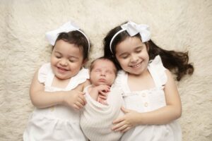 Newborn Baby Boy with Big Sisters Laying Down