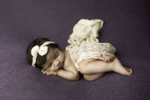 Newborn Baby Girl snuggled on purple 