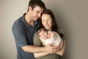 Newborn Baby Girl with mom and dad with their eyes closed 