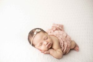 Newborn Baby Girl on White Blanket with pink wrap