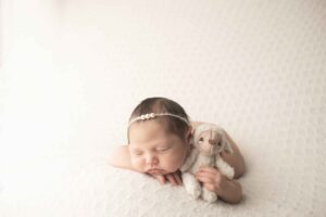 Newborn Baby Girl on White Blanket with pink wrap with lamb stuffy