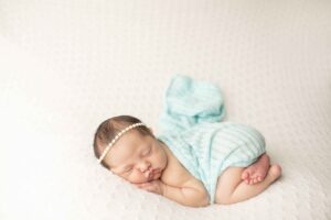 Newborn Baby Girl on White Blanket with pink wrap with blue wrap