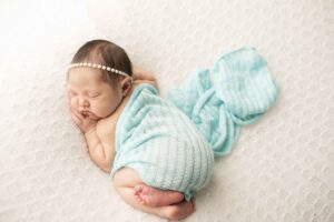 Newborn Baby Girl on White Blanket with blue wrap