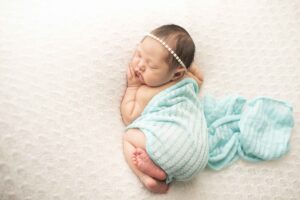 Newborn Baby Girl on White Blanket with blue wrap