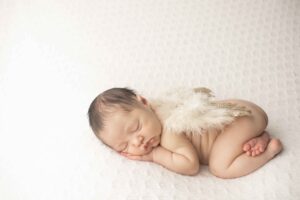 Newborn Baby Girl on White Blanket with angel wings