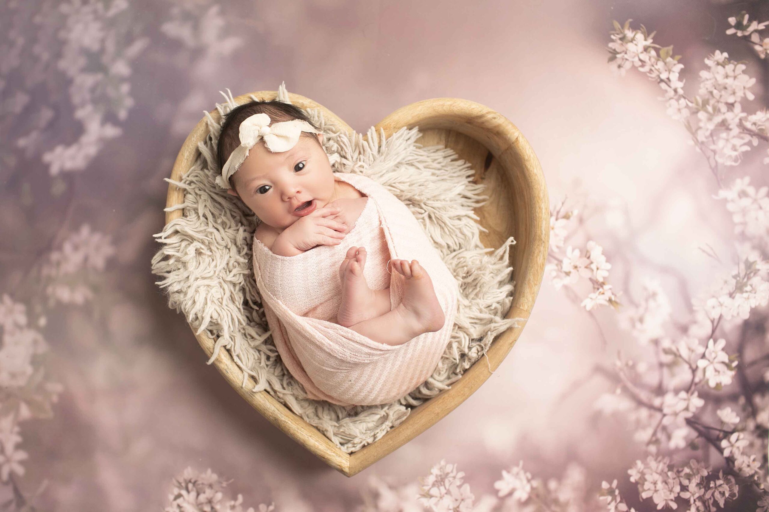 Newborn Baby Girl in heart bowl on purple flowers