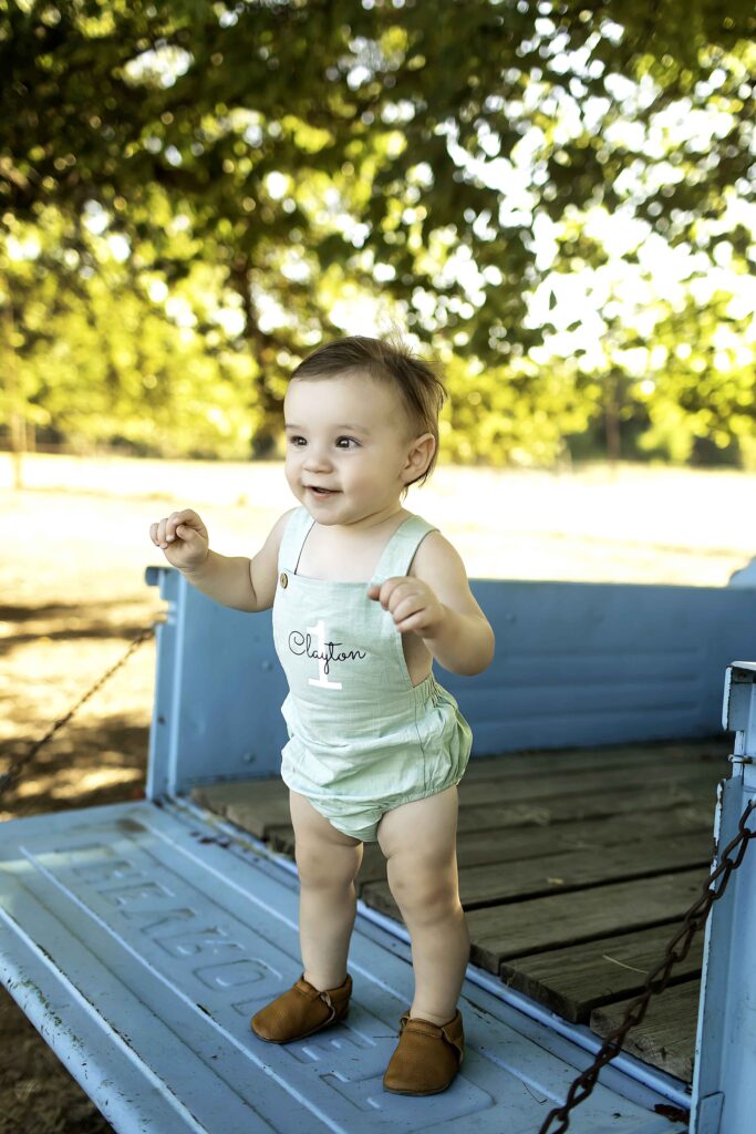 Young kid posing by the classic old blue truck on a sunny day