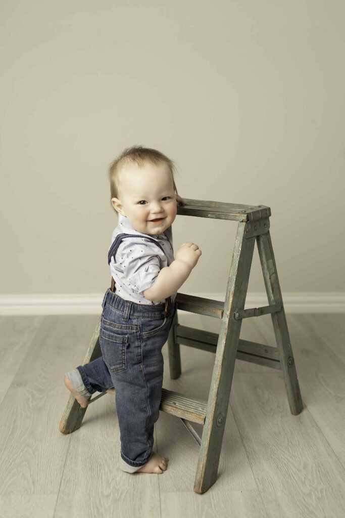 Twins posing with a mini ladder in the studio, showcasing their playful personalities in a charming and fun setup, captured by Chunky Monkey Photography