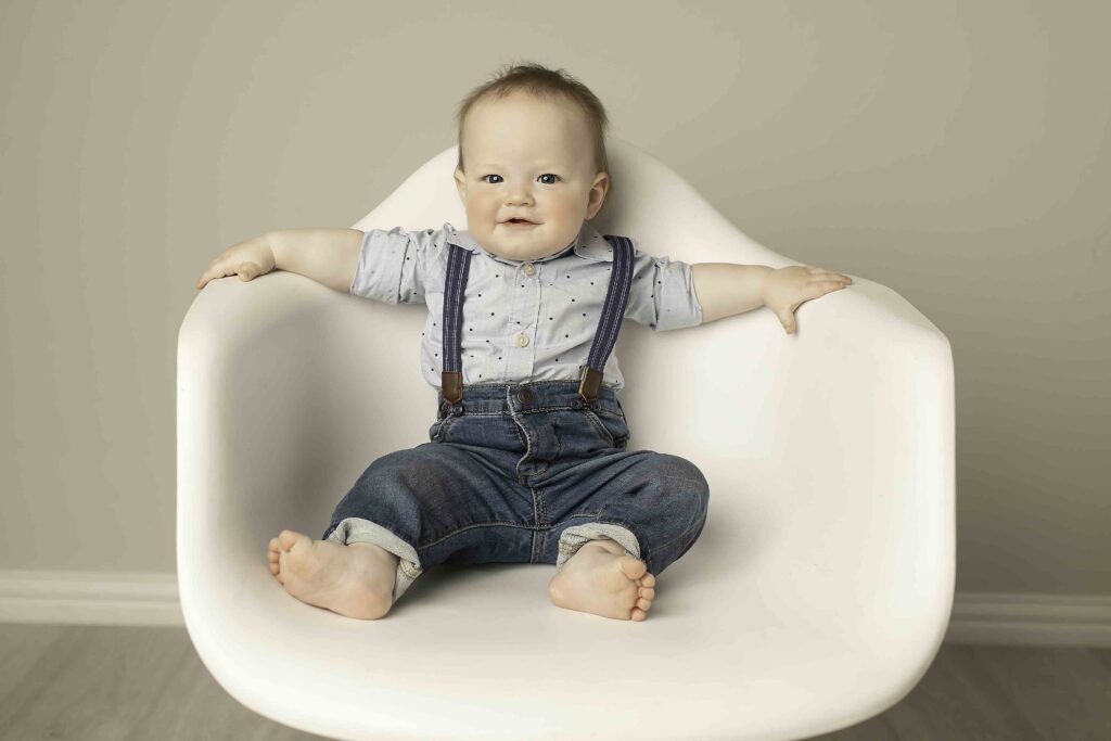 Twins sitting adorably on a white chair in the studio, captured in a serene moment of sweetness by Chunky Monkey Photography