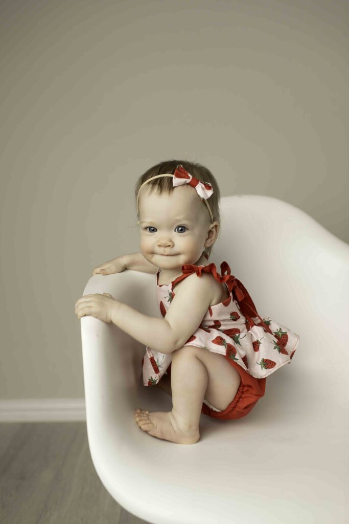 Elegant twin shot in the studio with both siblings posing on a white chair, beautifully captured by Chunky Monkey Photography