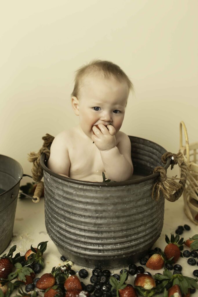 Twins enjoying a fun strawberry bath during their birthday shoot at Chunky Monkey Photography, surrounded by fresh strawberries and bubbly water, capturing their adorable smiles and playful moments.