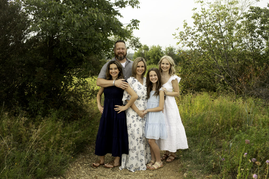 At Tandy Hills in Fort Worth, a family of five shares an intimate moment in nature, with three sisters celebrating their bond as the oldest prepares to begin her college adventure