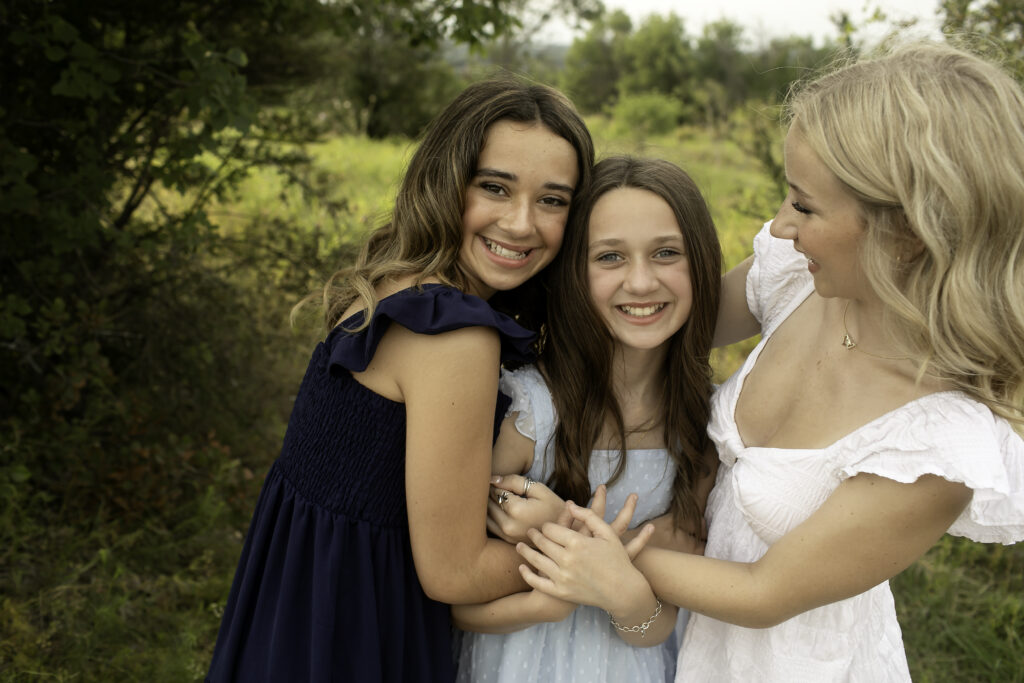 Three sisters holding hands at Tandy Hills, Fort Worth, symbolizing their unity as they face new adventures together