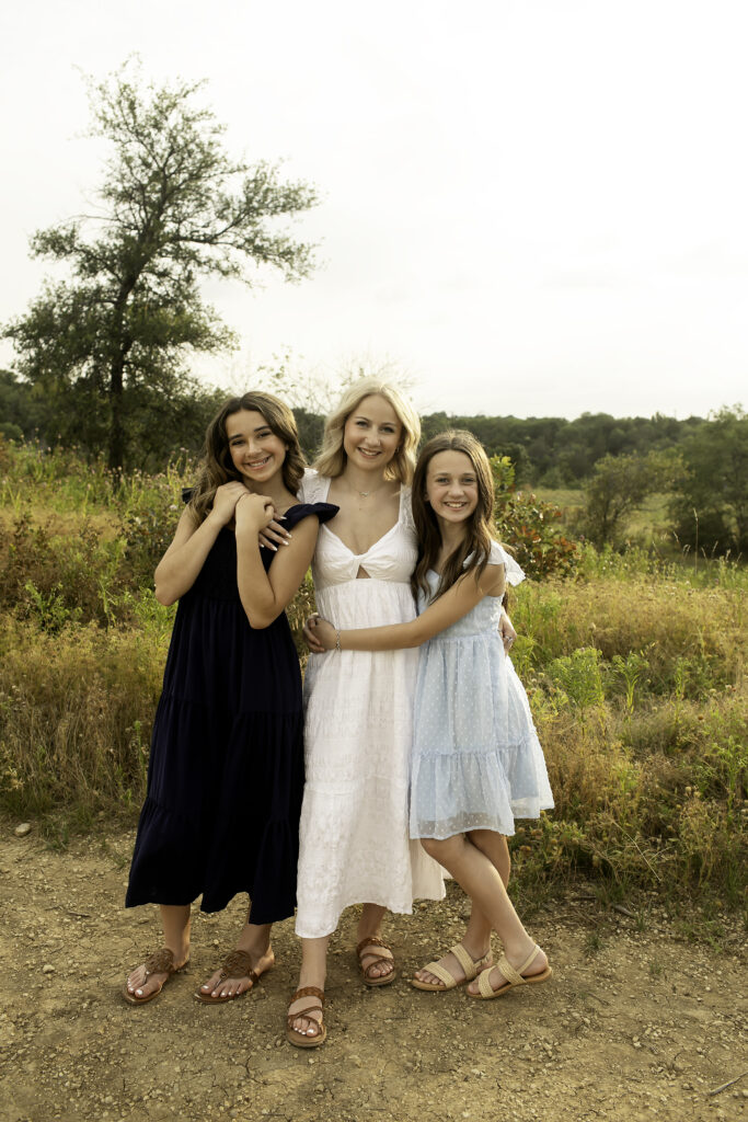 Three sisters creating lasting memories at Tandy Hills, surrounded by wildflowers and the warmth of the sun