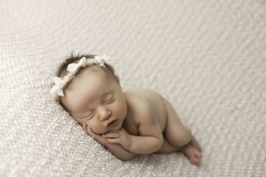 A delicate newborn peacefully posed on a soft, plush blanket, captured in a minimalist, timeless moment by Chunky Monkey Photography