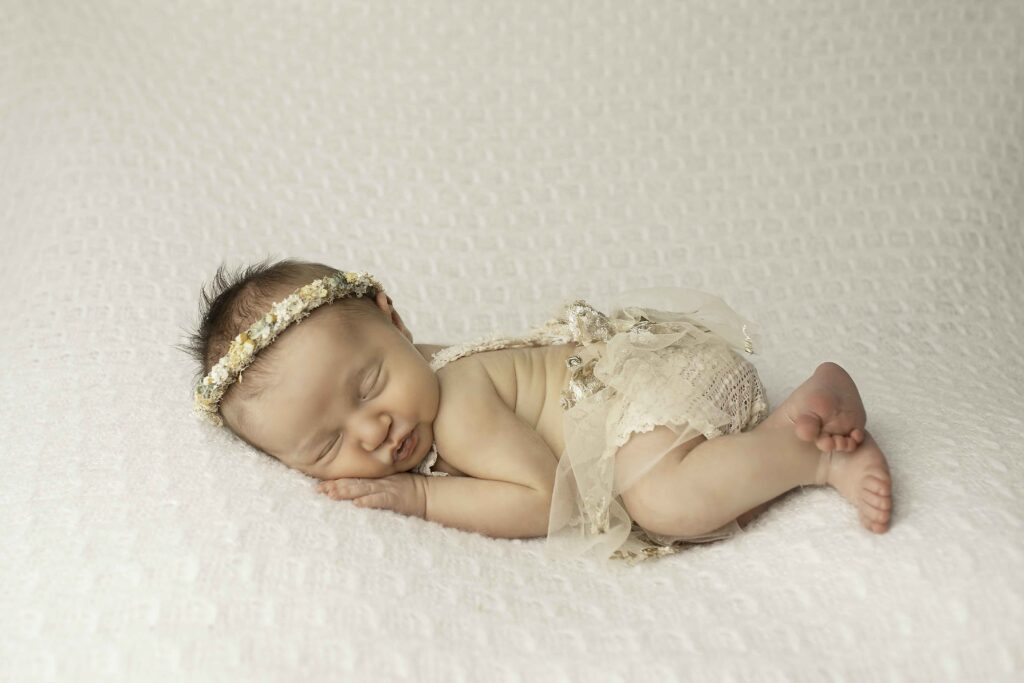 A newborn girl curled up gently on a cozy blanket, showcasing a peaceful and timeless pose, beautifully captured by Chunky Monkey Photography