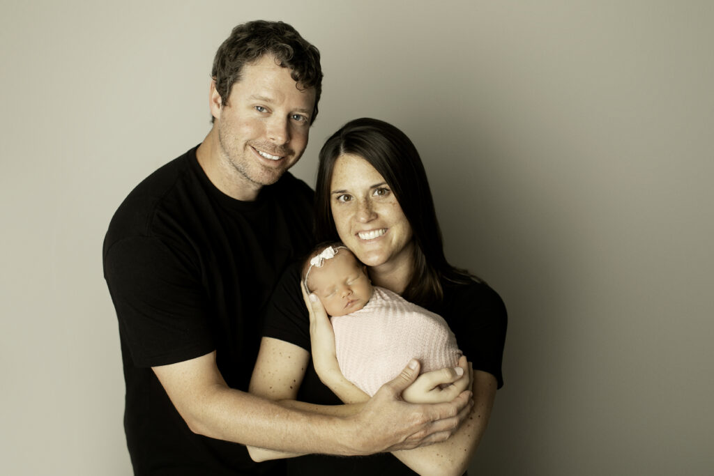 A heartwarming family moment with mom, dad, and their newborn daughter, all gathered together in love and joy, captured by Chunky Monkey Photography.