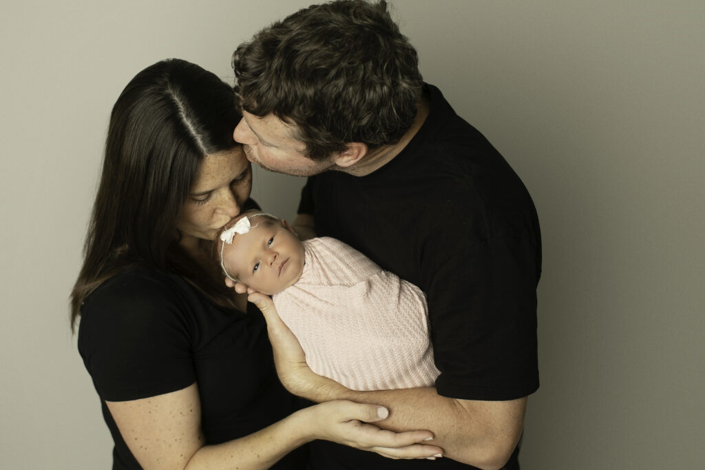 Mom, dad, and their newborn girl share a tender moment, capturing the love and connection of their growing family, beautifully shot by Chunky Monkey Photography