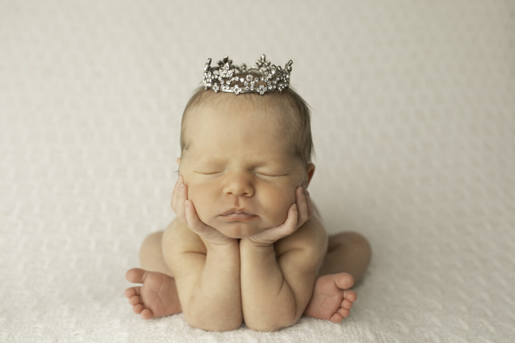 A newborn girl wrapped in softness, lying on a pure white blanket, captured in a simple, delicate pose by Chunky Monkey Photography