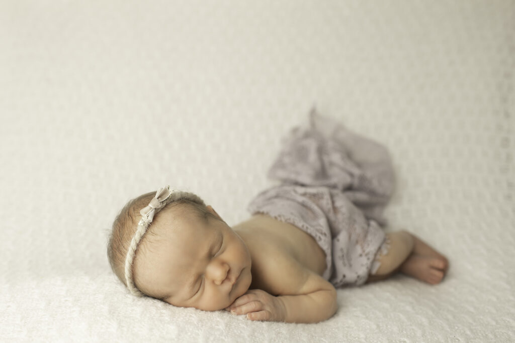 A newborn girl wrapped in a soft, cozy blanket, posed gently and beautifully captured by Chunky Monkey Photography