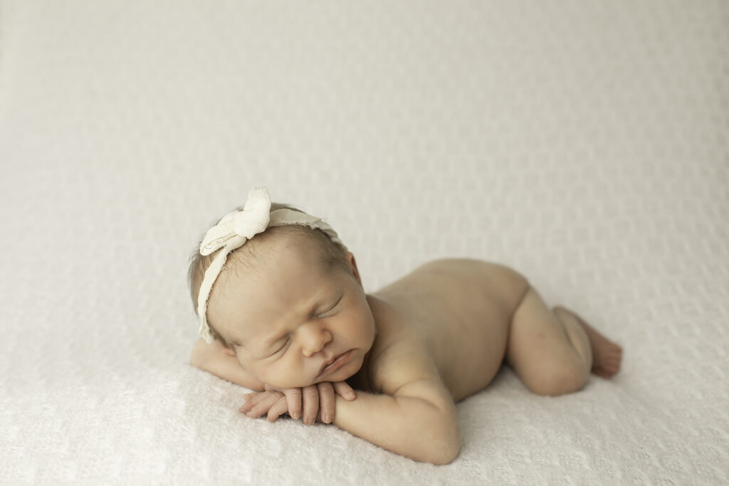 A newborn girl resting peacefully on a plush blanket, captured in a simple, serene pose that radiates calm, shot by Chunky Monkey Photography