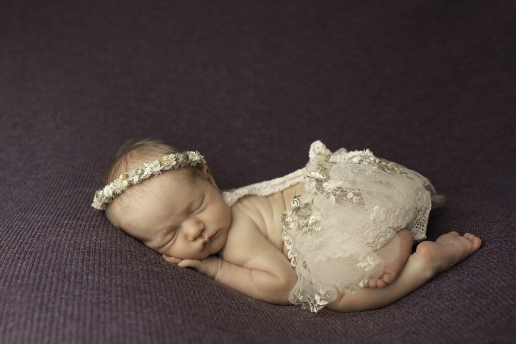 A simple and timeless pose of a newborn girl curled up on a soft blanket, captured beautifully by Chunky Monkey Photography