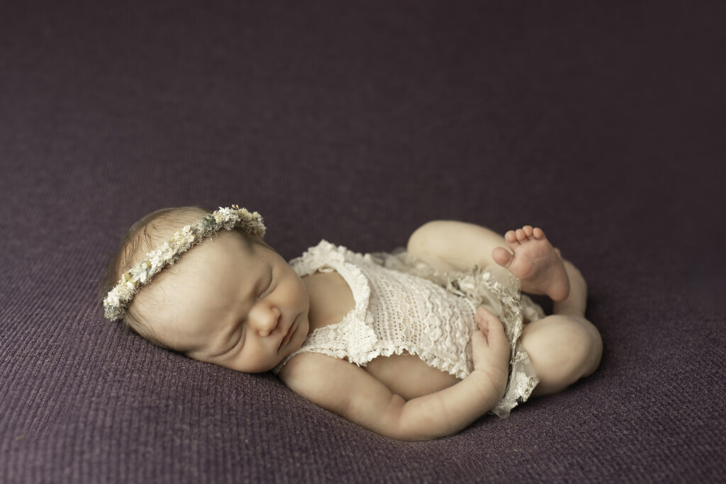 A newborn girl peacefully resting on a soft blanket, captured in a simple yet beautiful pose by Chunky Monkey Photography