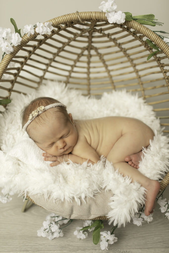 Chunky Monkey Photography captures the beauty of a newborn girl lying comfortably in a wicker basket, showcasing her delicate features in a peaceful pose