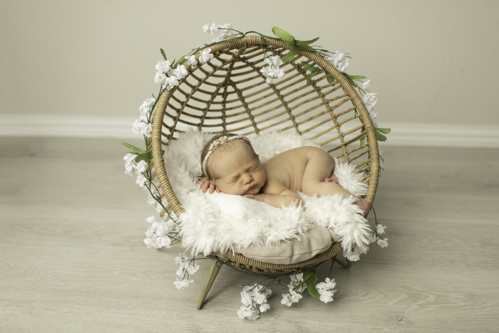 "In a wicker basket, a newborn girl is peacefully posed, wrapped in a cozy blanket, captured beautifully by Chunky Monkey Photography