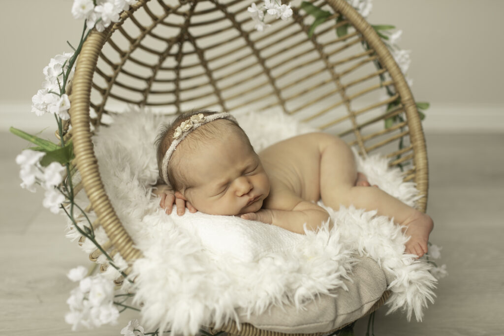 A precious newborn girl resting in a wicker basket, surrounded by softness and warmth, captured in a timeless moment by Chunky Monkey Photography