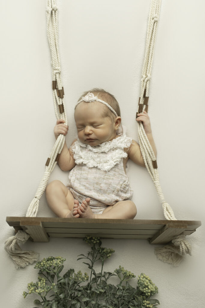 A serene moment captured as a newborn girl gently swings, swaddled in soft fabric, photographed beautifully by Chunky Monkey Photography