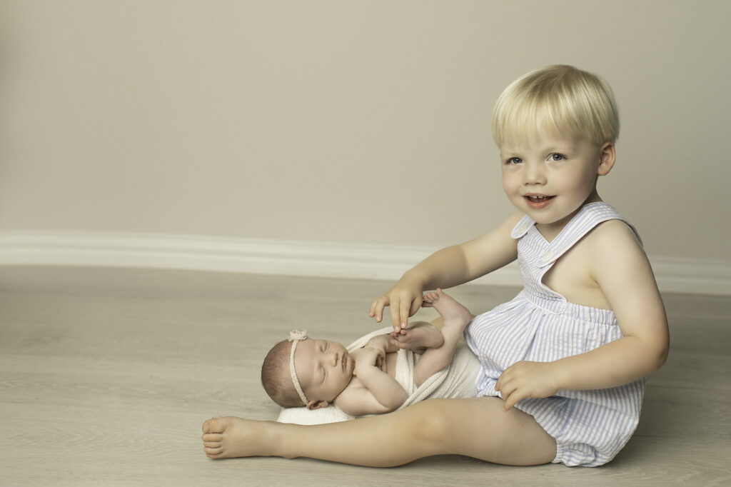 he bond between a big brother and his newborn sister shines through in this heartwarming moment, with both siblings captured lovingly in the Chunky Monkey Photography studio