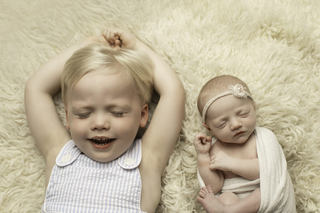 A big brother lovingly gazes at his newborn sister, both captured in a precious moment together, beautifully shot by Chunky Monkey Photography