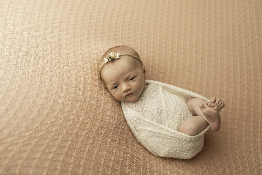 A newborn girl lying comfortably on a pink blanket, her innocence and tranquility highlighted in this simple, elegant pose by Chunky Monkey Photography.