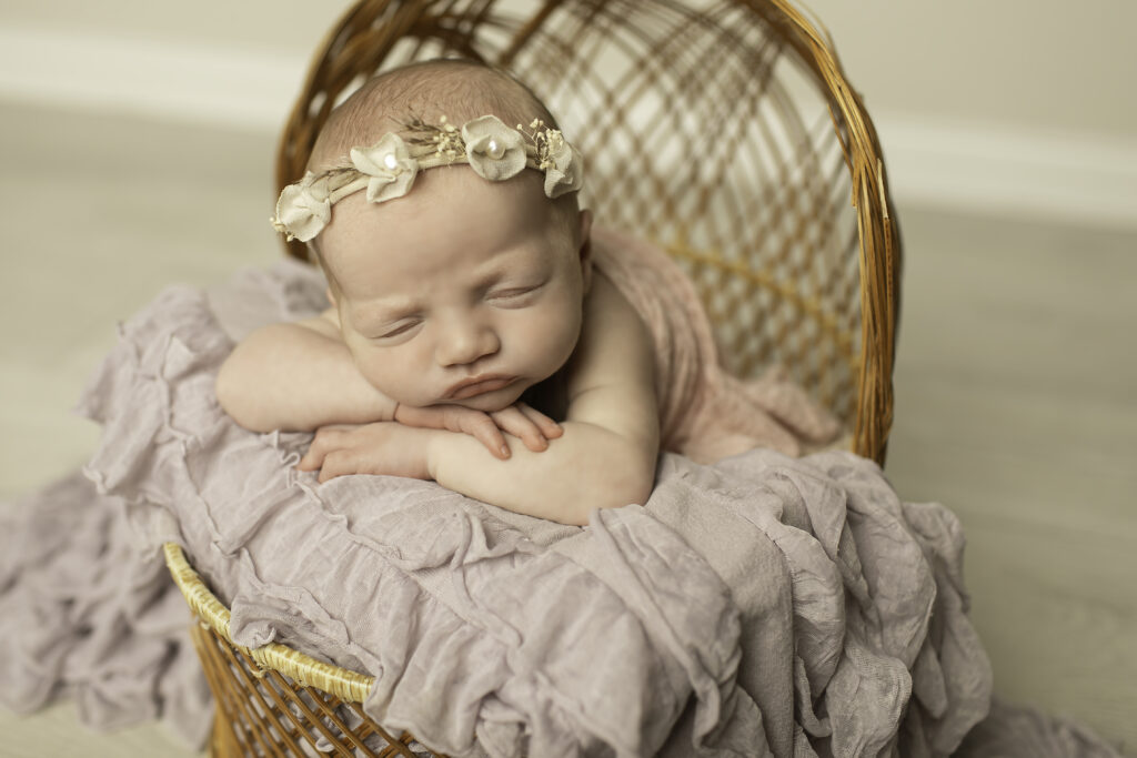 A sweet newborn girl lying gently in a wicker basket, surrounded by warmth and simplicity, photographed beautifully by Chunky Monkey Photography